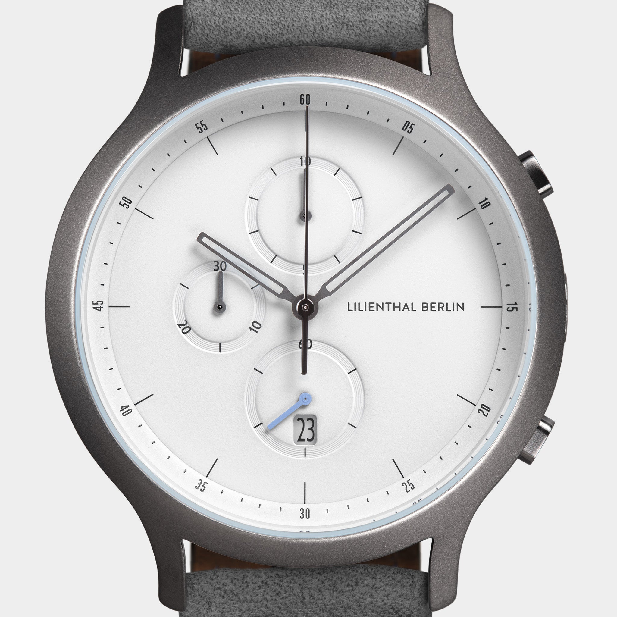 Minimalist silver chronograph watch with white dial, subdials, date display, and grey leather strap