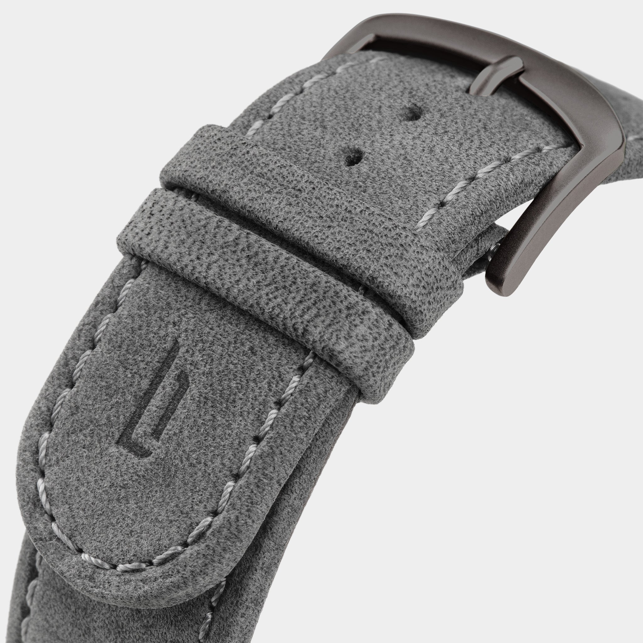 Close-up of a grey suede watch strap with stitching and metal buckle