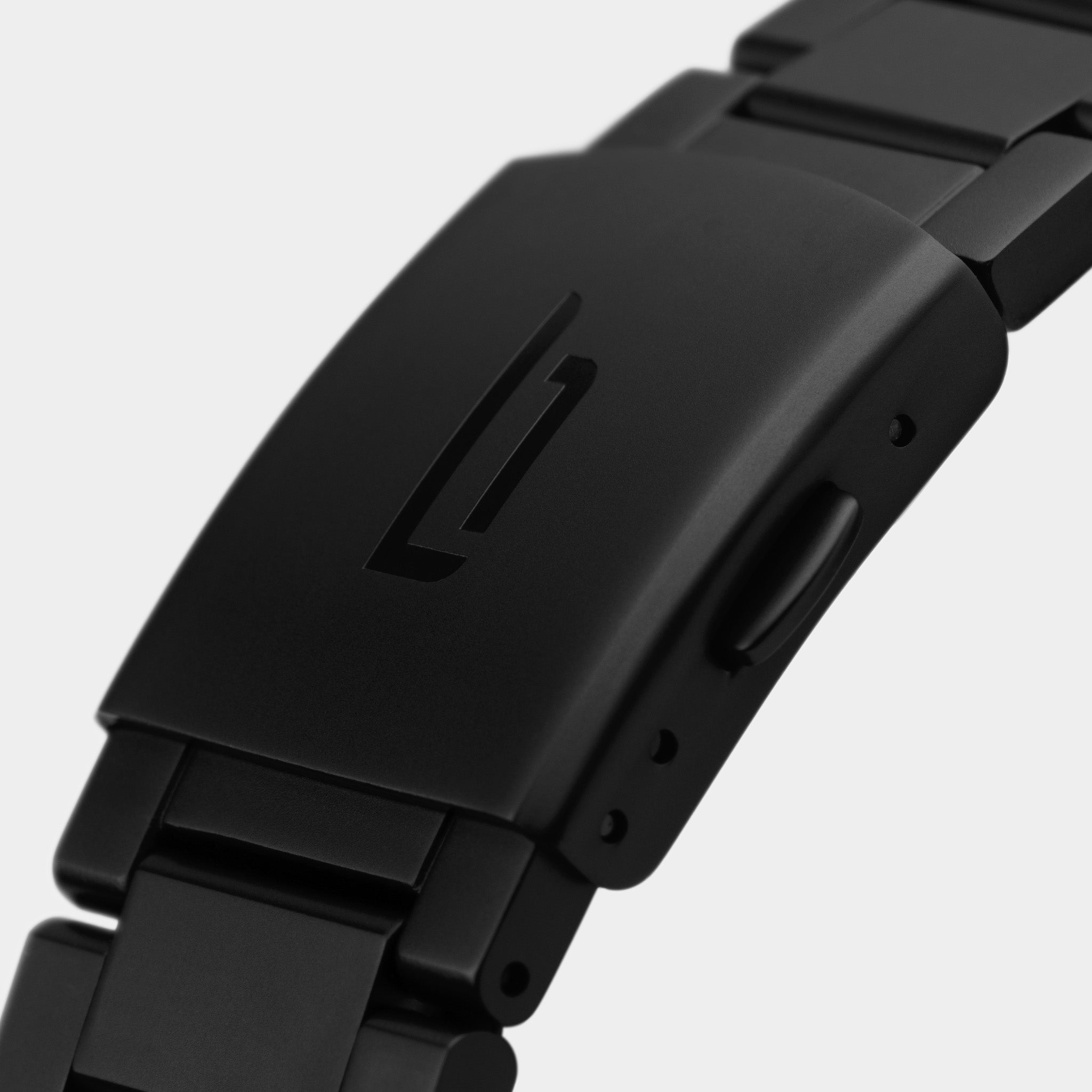 Close-up of a matte black metal watch clasp with engraved logo, minimalist design