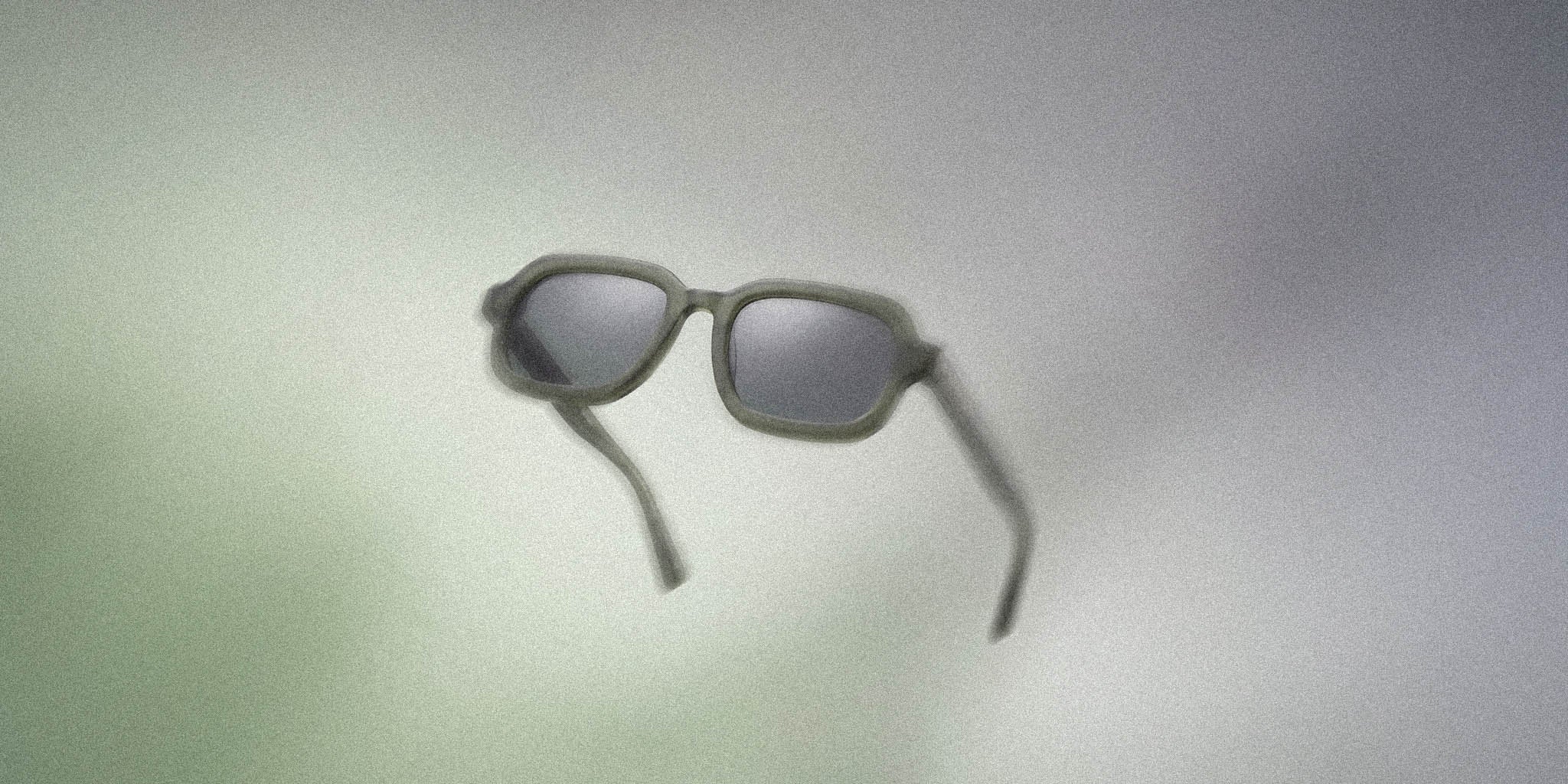Modern square sunglasses with matte frame and dark lenses on a soft gradient background