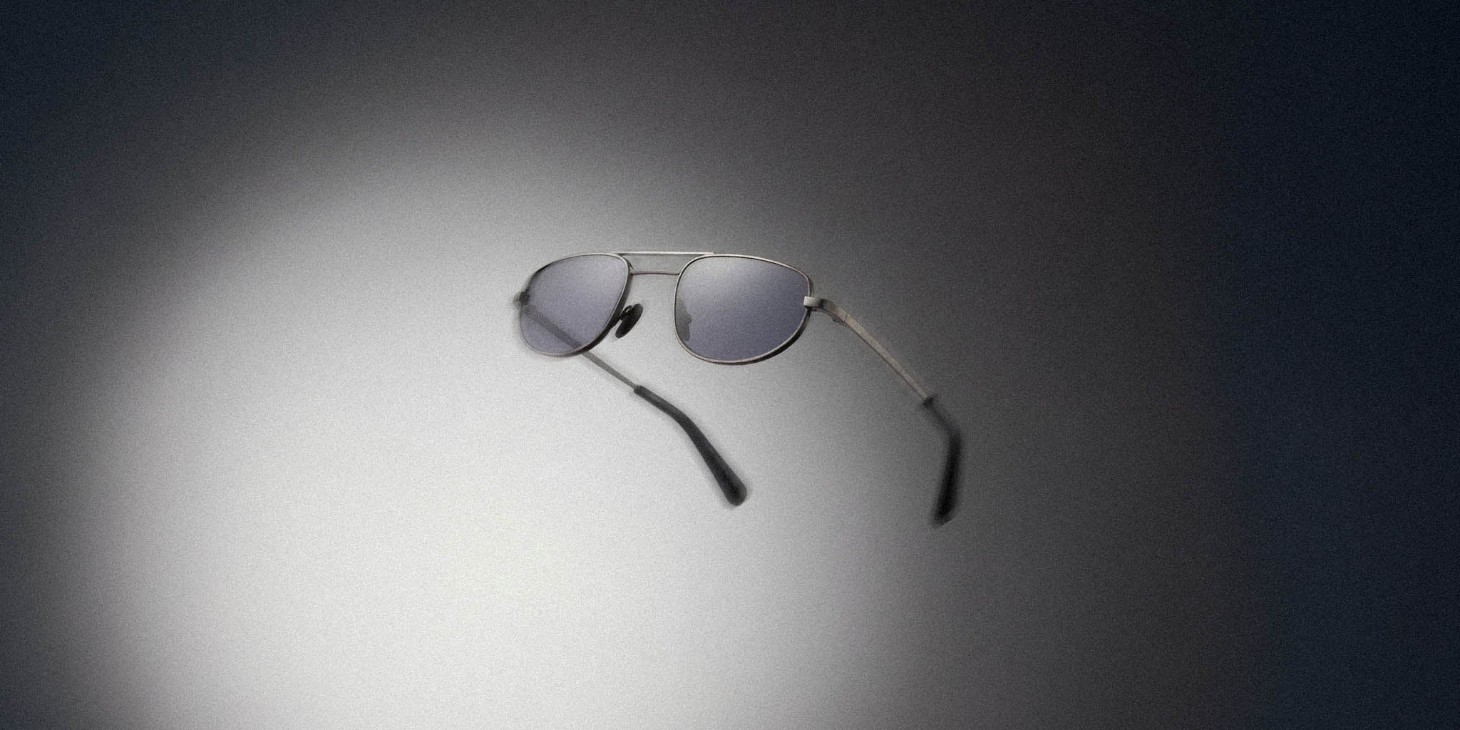 Modern aviator sunglasses with silver frame and grey lenses on a gradient background