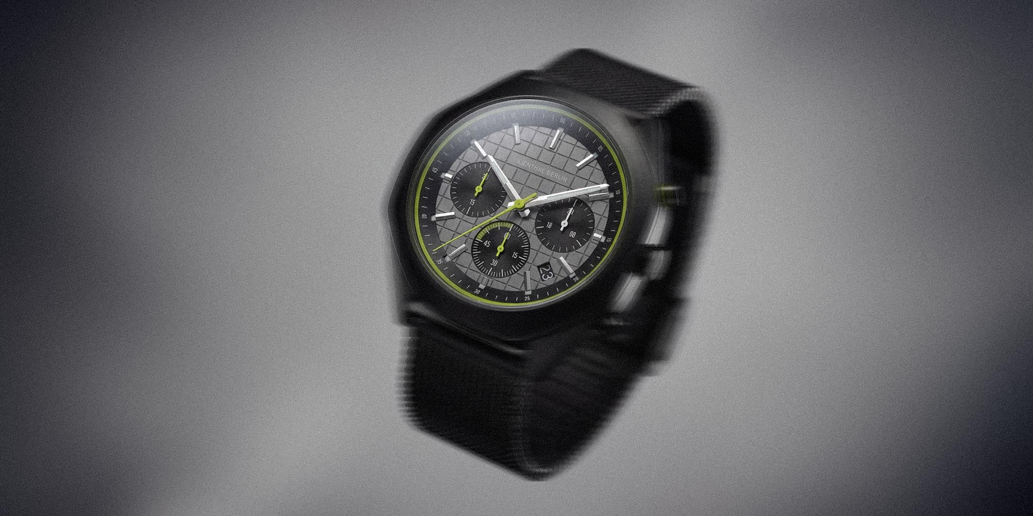 Black and lime chronograph watch with mesh strap, three subdials, and sleek geometric dial.