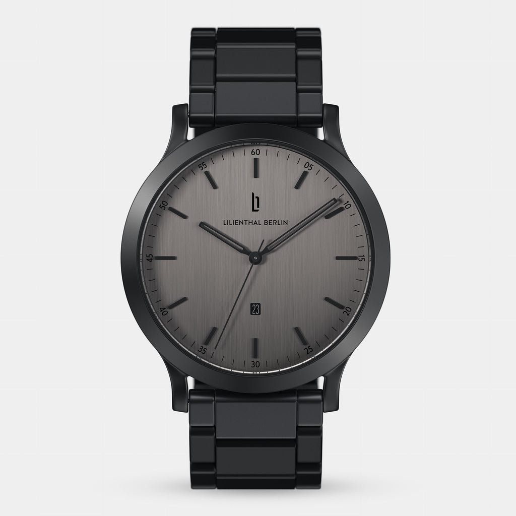 Minimalist black metal wristwatch with grey brushed dial and date display on white background