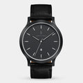 Minimalist black wristwatch with leather strap and date window, modern dial design