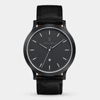 Minimalist black wristwatch with leather strap and date window, modern dial design