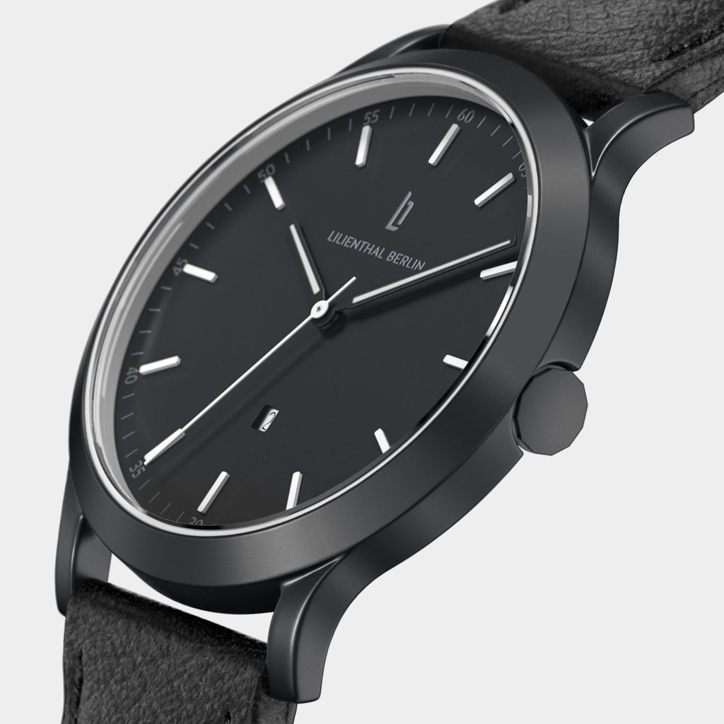 Minimalist black analog wristwatch with black leather strap and silver hour markers