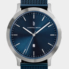 Minimalist blue dial watch with silver case, mesh strap, and date display