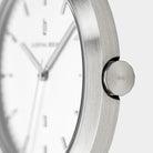 Close-up of minimalist silver watch with brushed stainless steel case and white dial