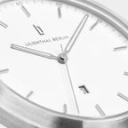 Minimalist silver and white wristwatch close-up with date display and sleek hands
