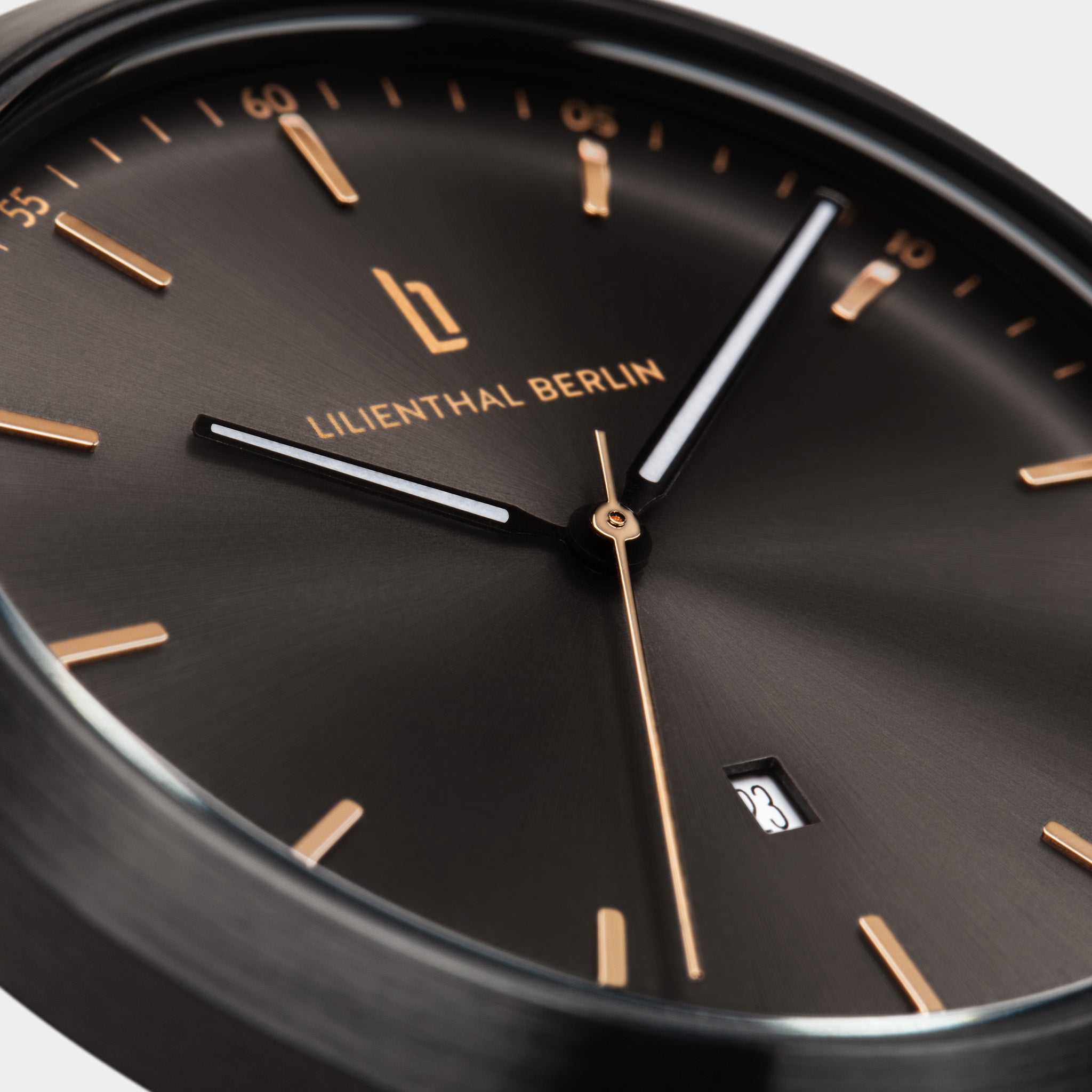Close-up of a minimalist black watch face with gold markers and date display