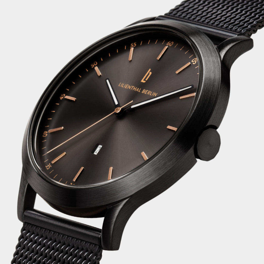 Black stainless steel watch with mesh band, minimalist dial, rose gold accents, date display