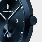 Close-up of minimalist dark blue watch face with white markers and subdial