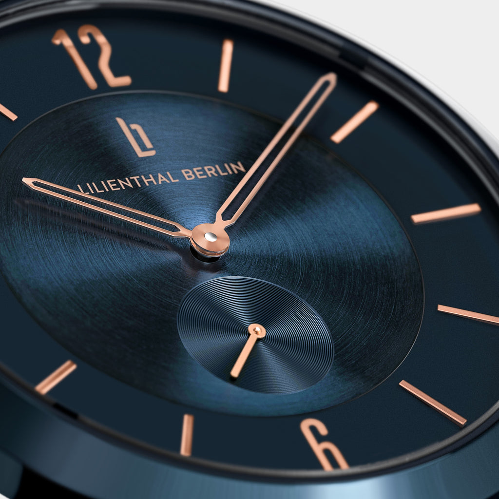Close-up of a modern blue watch face with rose gold hands and hour markers